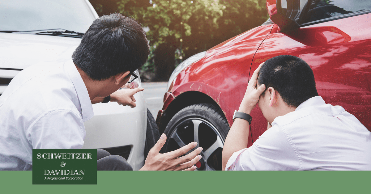 two men pointing at car accident scene in sun