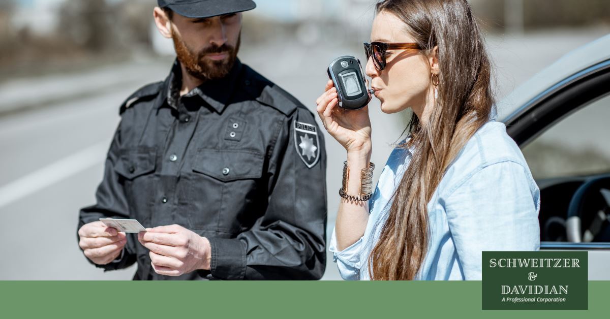 woman blowing into breathalyzer and cop watching